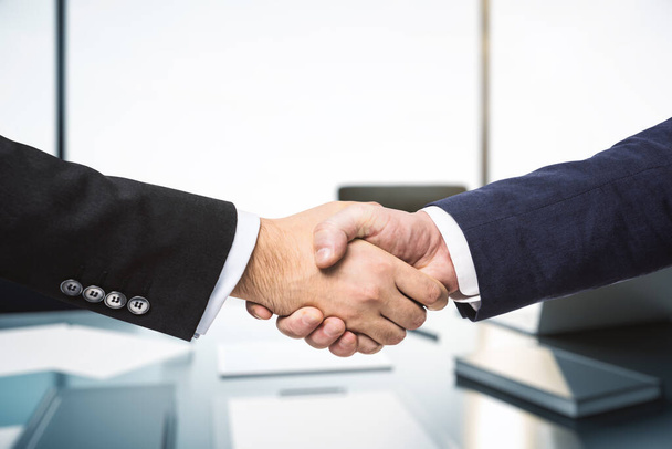Handshake of two businessmen in sunny modern office, partnership concept, close up - Photo, image