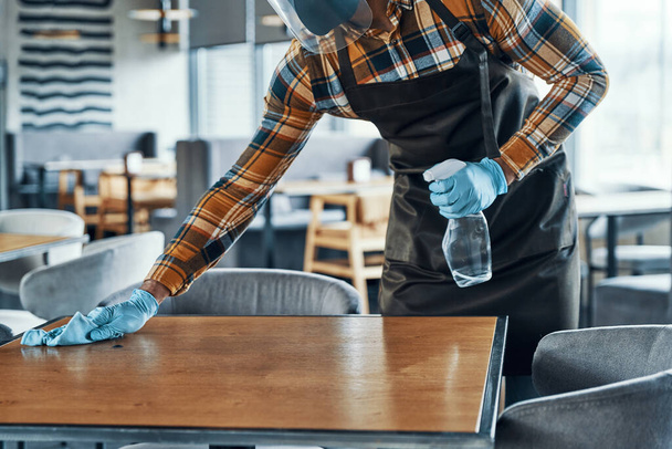 Close up of man in protective gloves cleaning table in restaurant - Foto, Imagem
