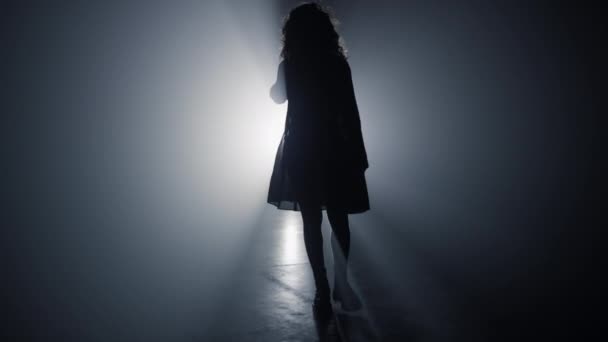 Karanlıkta yürüyen siluet kadın. Projektör arka planında yürüyen kız. - Video, Çekim