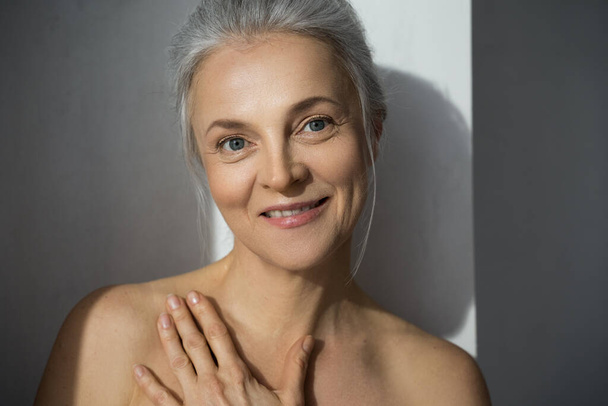 Mature woman smiling with hand on her chest - Foto, Imagen