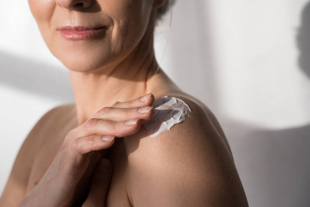 Woman applying cosmetic cream on clean hydrated skin - Fotó, kép