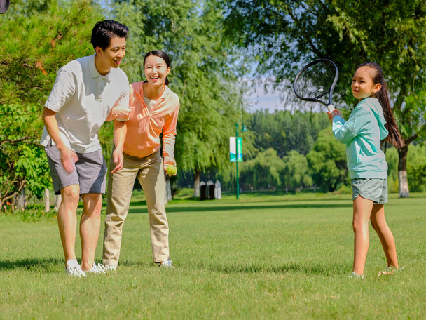 Happy family of three playing tennis in the park - Φωτογραφία, εικόνα