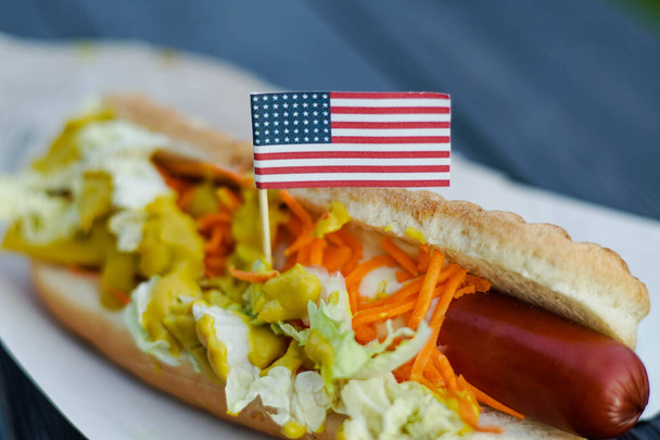 Hot dog mustárral és az Amerikai Egyesült Államok kis zászlajával. A függetlenség napja július 4-én az USA-ban - Fotó, kép