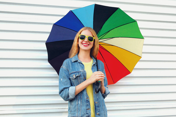 Portrait of happy smiling young woman with colorful umbrella on a white background - Фото, зображення