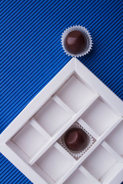 Vertical shot of chocolate box with brown candies on blue background. - Foto, immagini