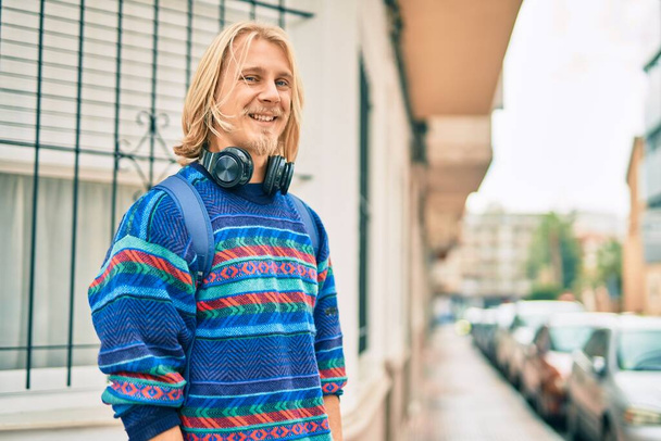Fiatal skandináv diák férfi mosolyog boldog használ fejhallgató a városban. - Fotó, kép