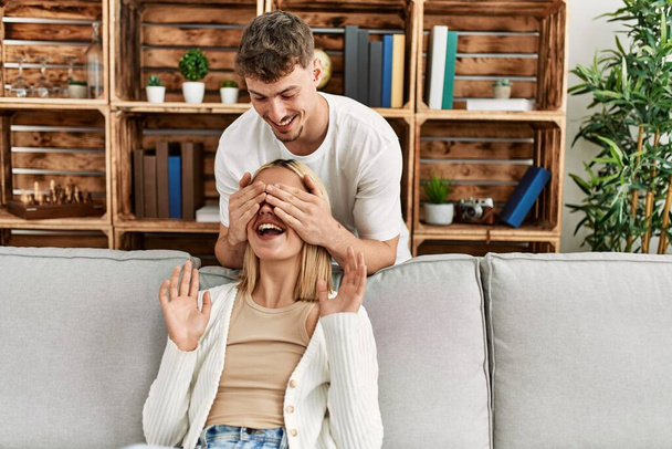 Homme surprenant sa petite amie avec les mains sur les yeux à la maison. - Photo, image