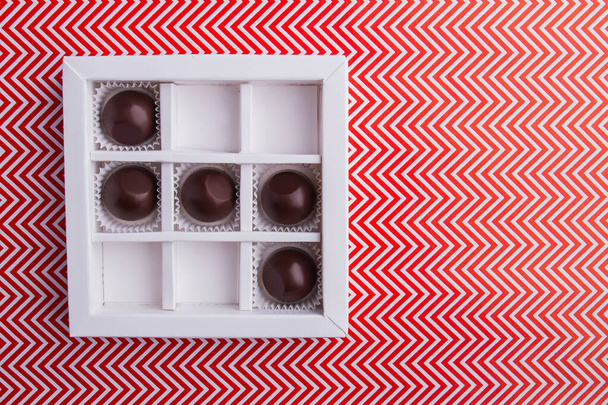 White square box with round chocolate candies. - 写真・画像