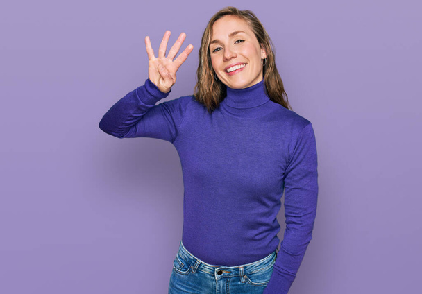 jonge blonde vrouw dragen casual kleding tonen en wijzen met vingers nummer vier terwijl glimlachen zelfverzekerd en gelukkig.  - Foto, afbeelding