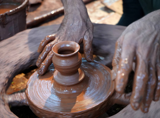 Manos de un alfarero, creando un frasco de tierra en la rueda. Un alfarero guiando a las manos de la mujer  - Foto, Imagen