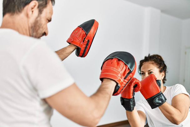 Mediana edad pareja hispana sonriendo feliz entrenamiento boxeo en casa. - Foto, Imagen