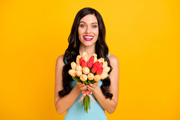 Photo of cheerful lady hold bunch flowers look camera wear blue top isolated yellow color background - Fotografie, Obrázek