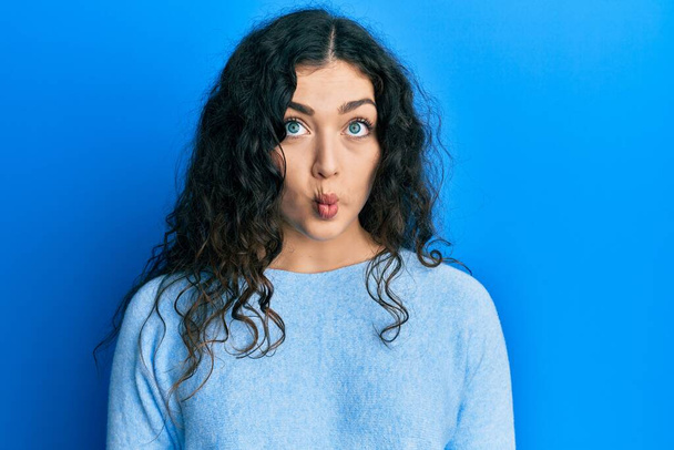 Young brunette woman with curly hair wearing casual clothes making fish face with lips, crazy and comical gesture. funny expression.  - Foto, afbeelding