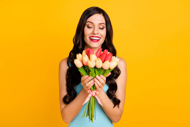 Photo of cheerful lady hold bunch flowers toothy beaming smile wear blue dress isolated yellow color background - Foto, imagen