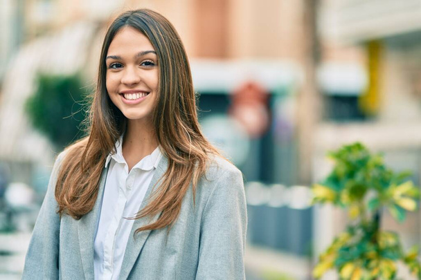 Jonge latijnse zakenvrouw glimlachend blij staande in de stad. - Foto, afbeelding