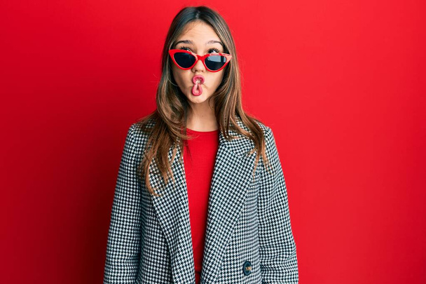 Young brunette woman wearing fashion and modern look making fish face with lips, crazy and comical gesture. funny expression.  - Foto, immagini