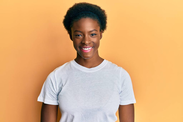 Nuori afrikkalainen amerikkalainen tyttö yllään rento valkoinen t paita onnellinen ja viileä hymy kasvoilla. onnekas henkilö.  - Valokuva, kuva