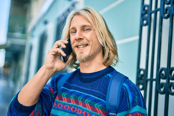 Jeune étudiant scandinave souriant heureux de parler sur le smartphone de la ville. - Photo, image