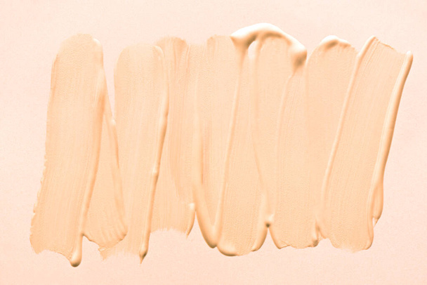 Make up base or bb cream strokes close up. Beige color corrector, concealer, foundation smudged brushstrokes as texture. - Fotó, kép