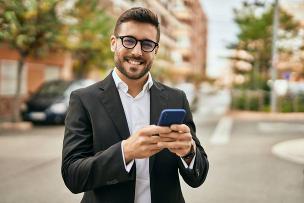 Young hispanic businessman smiling happy using smartphone at the city. - Fotó, kép