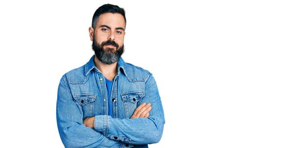 Hispanic man with beard wearing casual denim jacket happy face smiling with crossed arms looking at the camera. positive person.  - Фото, зображення