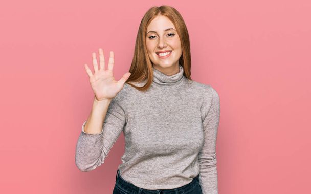 Joven mujer irlandesa con ropa casual mostrando y señalando hacia arriba con los dedos número cinco mientras sonríe confiado y feliz.  - Foto, Imagen