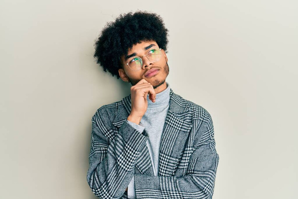 Joven afroamericano con cabello afro usando gafas de ropa casual pensando concentrado en la duda con el dedo en la barbilla y mirando hacia arriba preguntándose  - Foto, Imagen