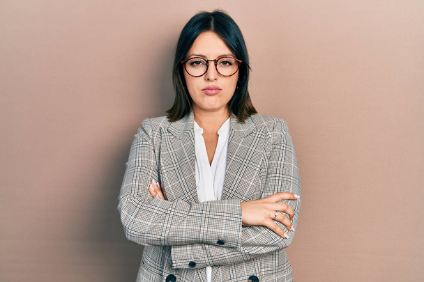 Young hispanic woman wearing business clothes and glasses skeptic and nervous, disapproving expression on face with crossed arms. negative person.  - Foto, afbeelding