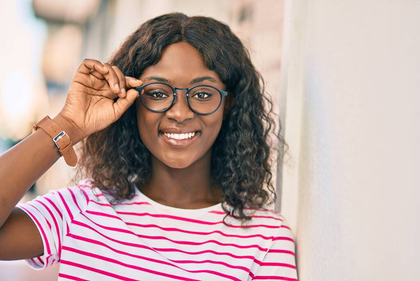 Νεαρή Αφροαμερικανή χαμογελαστή χαρούμενη που στέκεται στην πόλη. - Φωτογραφία, εικόνα