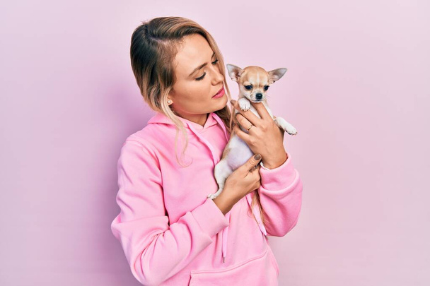 Young caucasian woman holding beautiful small chihuahua dog hugging and kissing pet with love - Foto, Imagen