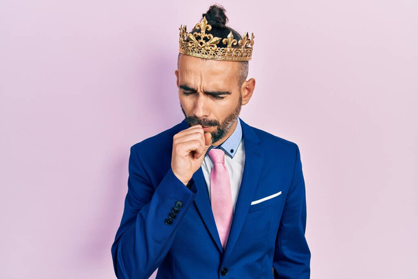 Young hispanic man wearing business clothes and king crown feeling unwell and coughing as symptom for cold or bronchitis. health care concept.  - Foto, imagen