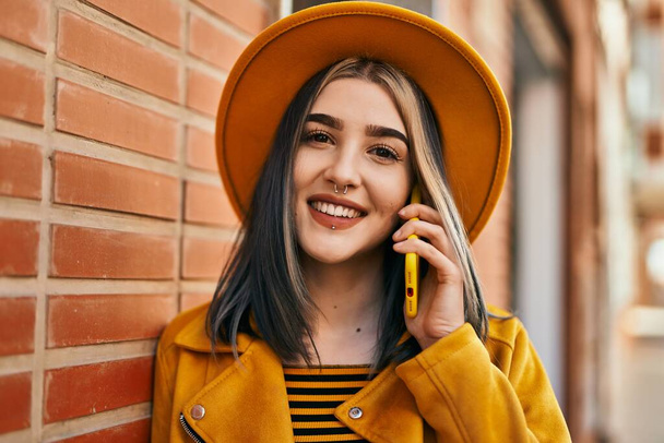 Jovem caucasiana sorrindo feliz falando no smartphone na cidade. - Foto, Imagem