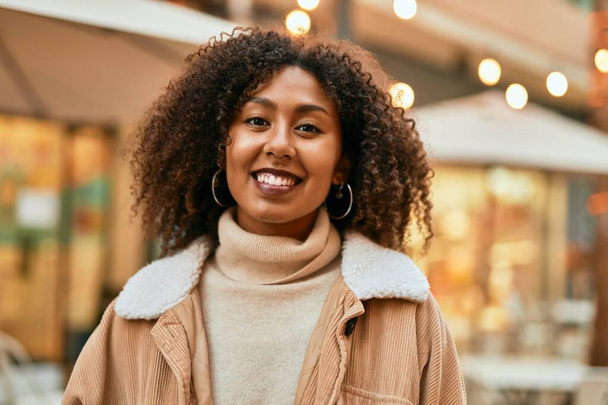 Jeune femme afro-américaine souriante heureuse debout à la ville. - Photo, image