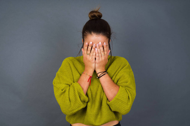 young Hispanic woman covering her face with her hands, being devastated and crying. Sad concept - Photo, Image