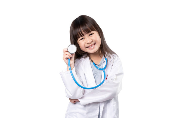 Uśmiechnięta dziewczynka w mundurze medycznym trzymająca stetoskop, opieka zdrowotna i koncepcja medyczna, odizolowana na białym tle ze ścieżką wycinania - Zdjęcie, obraz