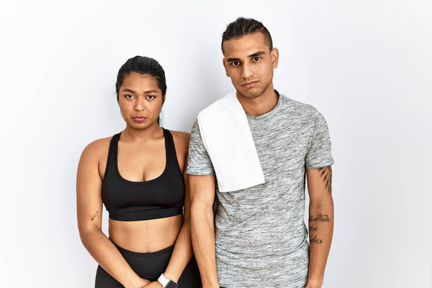 Young latin couple wearing sportswear standing over isolated background depressed and worry for distress, crying angry and afraid. sad expression.  - Zdjęcie, obraz