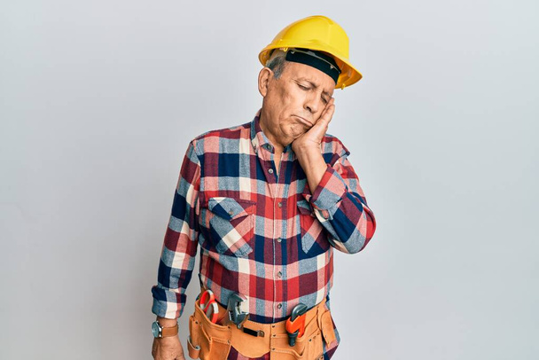 Hombre hispano mayor vistiendo uniforme de manitas pensando que parece cansado y aburrido con problemas de depresión con brazos cruzados.  - Foto, Imagen