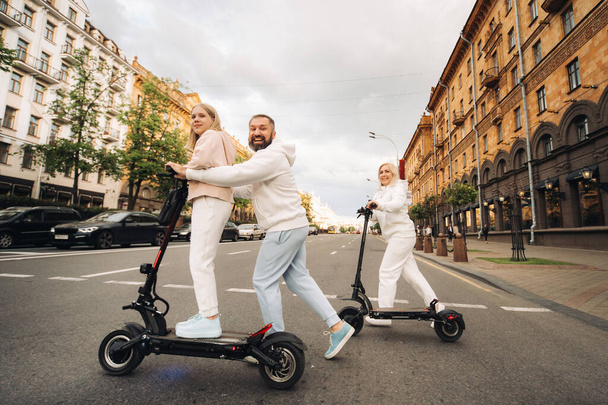 Une famille en vêtements blancs monte scooters électriques dans la ville.Activités de plein air. - Photo, image