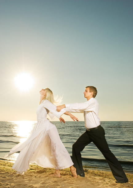 若いカップルの日没でビーチでダンス - 写真・画像