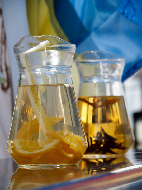 Orange cocktail in a transparent decanter with two straws on the background of an alternative beverage in the carafe without straws. About how the beverage type influences the way of its consumed. - Fotoğraf, Görsel