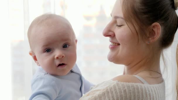 Aranyos kisfiú ölelgeti anyát és mosolyog a kamerában. A családi boldogság és a gyermekfejlődés fogalma - Felvétel, videó