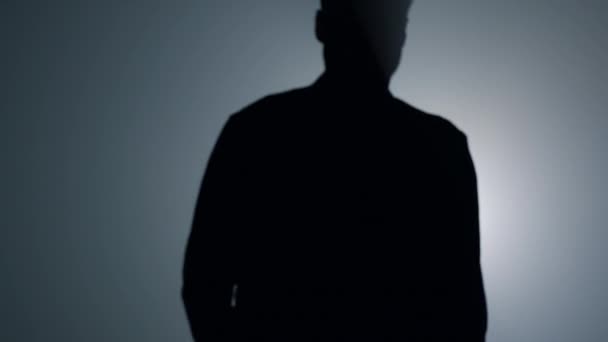 Silhouet man gaat weg op een donkere achtergrond. Terug uitzicht man wandelen in de duisternis. - Video