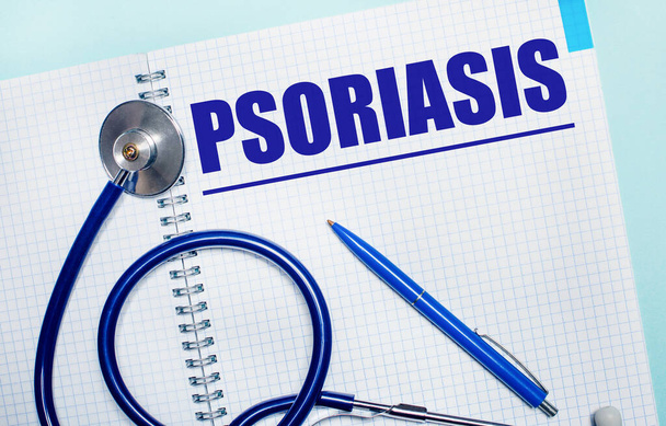 On a light blue background, an open notebook with the word PSORIASIS, a blue pen and a stethoscope. View from above. Medical concept - Fotoğraf, Görsel