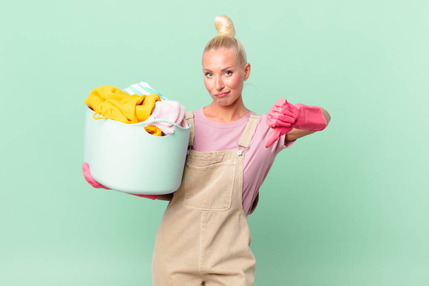 pretty blond woman feeling cross,showing thumbs down washing clothes concept - Foto, immagini