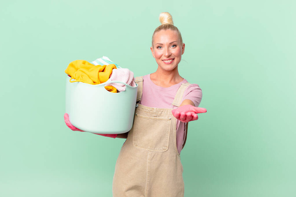 pretty blond woman smiling happily with friendly and  offering and showing a concept washing clothes concept - Zdjęcie, obraz