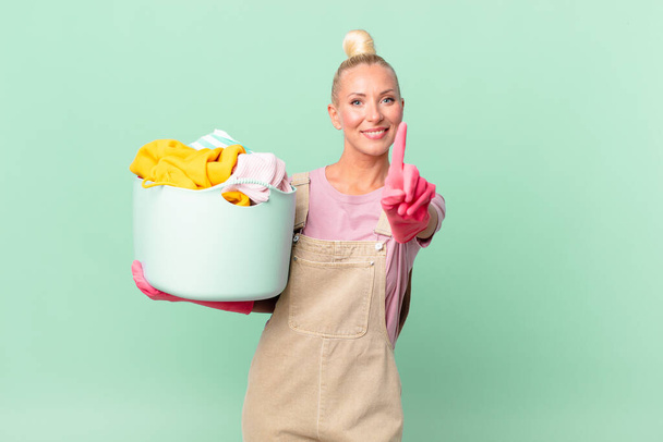 pretty blond woman smiling proudly and confidently making number one washing clothes concept - Photo, Image