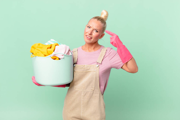 pretty blond woman feeling confused and puzzled, showing you are insane washing clothes concept - Zdjęcie, obraz