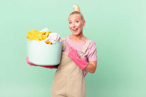 pretty blond woman looking excited and surprised pointing to the side washing clothes concept - Fotografie, Obrázek