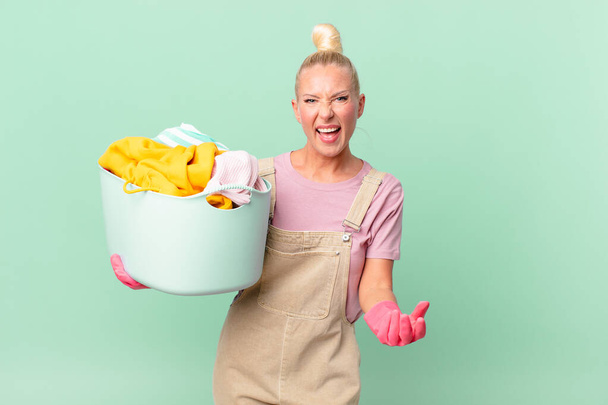 pretty blond woman looking desperate, frustrated and stressed washing clothes concept - 写真・画像