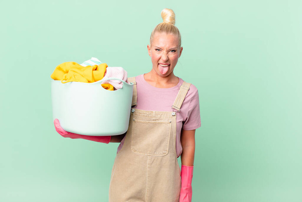 pretty blond woman feeling disgusted and irritated and tongue out washing clothes concept - Photo, Image